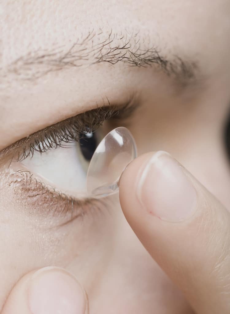 Frau beim Einsetzen einer Kontaktlinse ins Auge