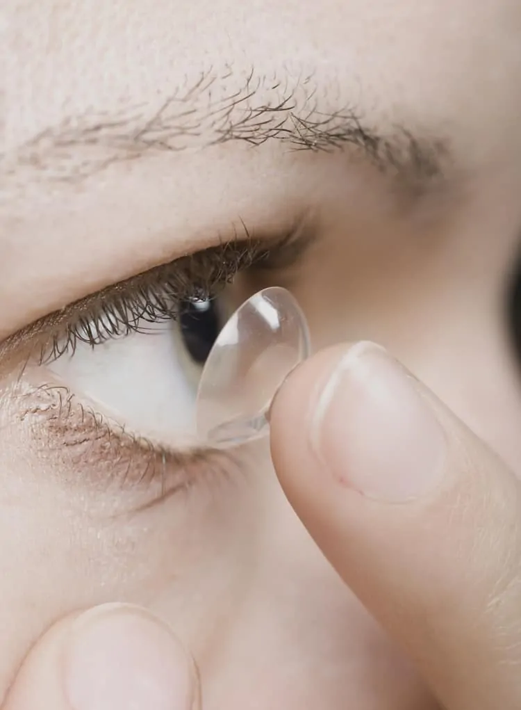 Frau beim Einsetzen einer Kontaktlinse ins Auge